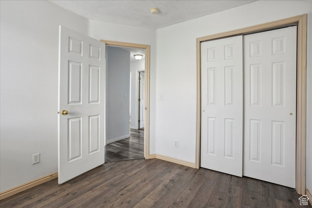 Unfurnished bedroom featuring dark wood-type flooring and a closet