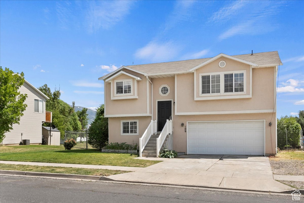 Bi-level home featuring an attached garage, concrete driveway, and stucco siding