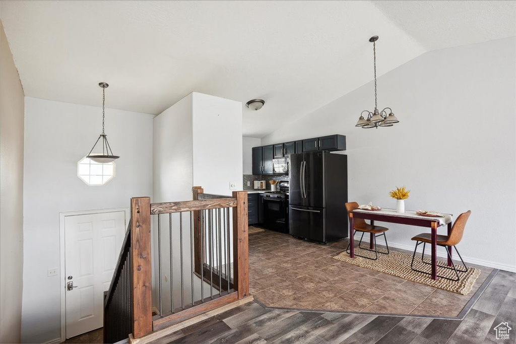 Kitchen with freestanding refrigerator, gas stove, a chandelier, dark wood finished floors, and hanging light fixtures