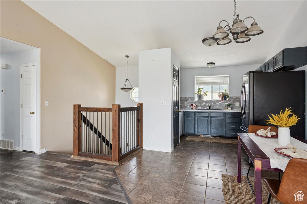 Kitchen with freestanding refrigerator, tasteful backsplash, a chandelier, light countertops, and decorative light fixtures