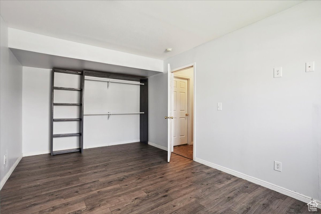Unfurnished bedroom with dark wood-style floors and a closet