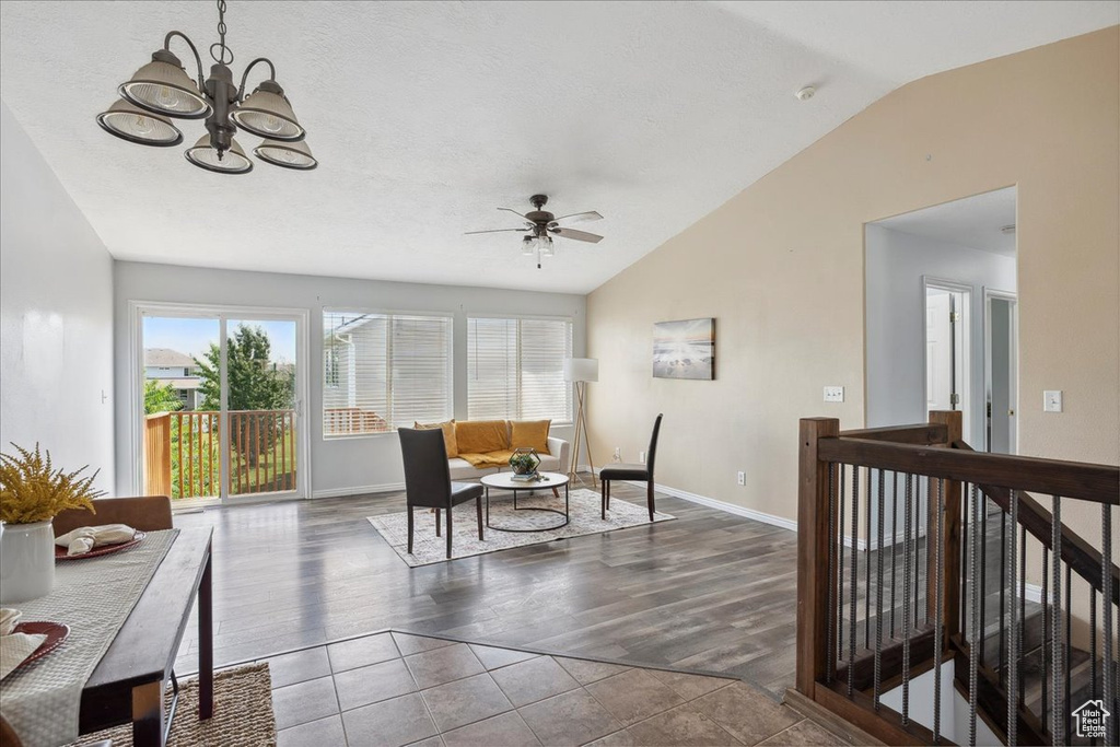 Living area with vaulted ceiling, ceiling fan, a chandelier, wood finished floors, and an upstairs landing