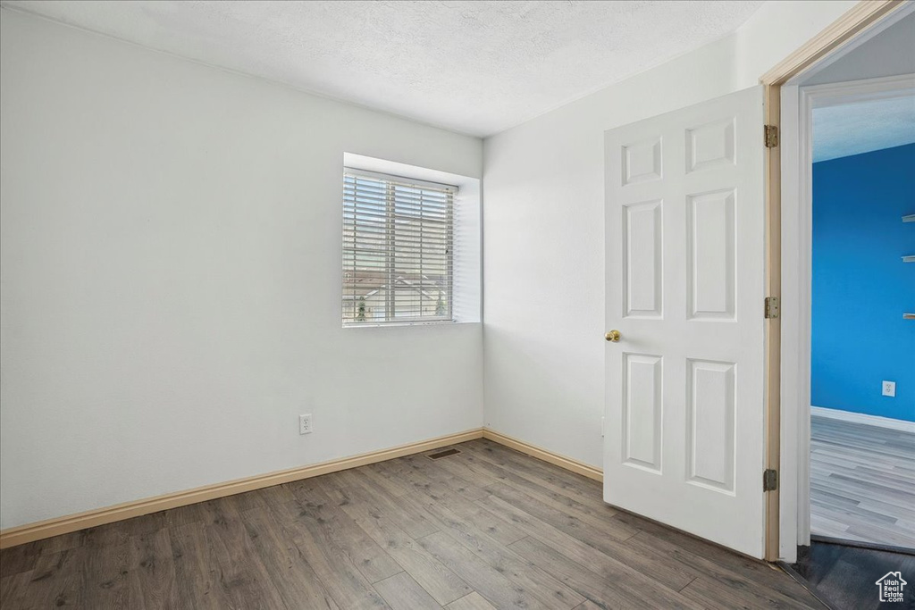 Unfurnished bedroom with wood finished floors and a textured ceiling