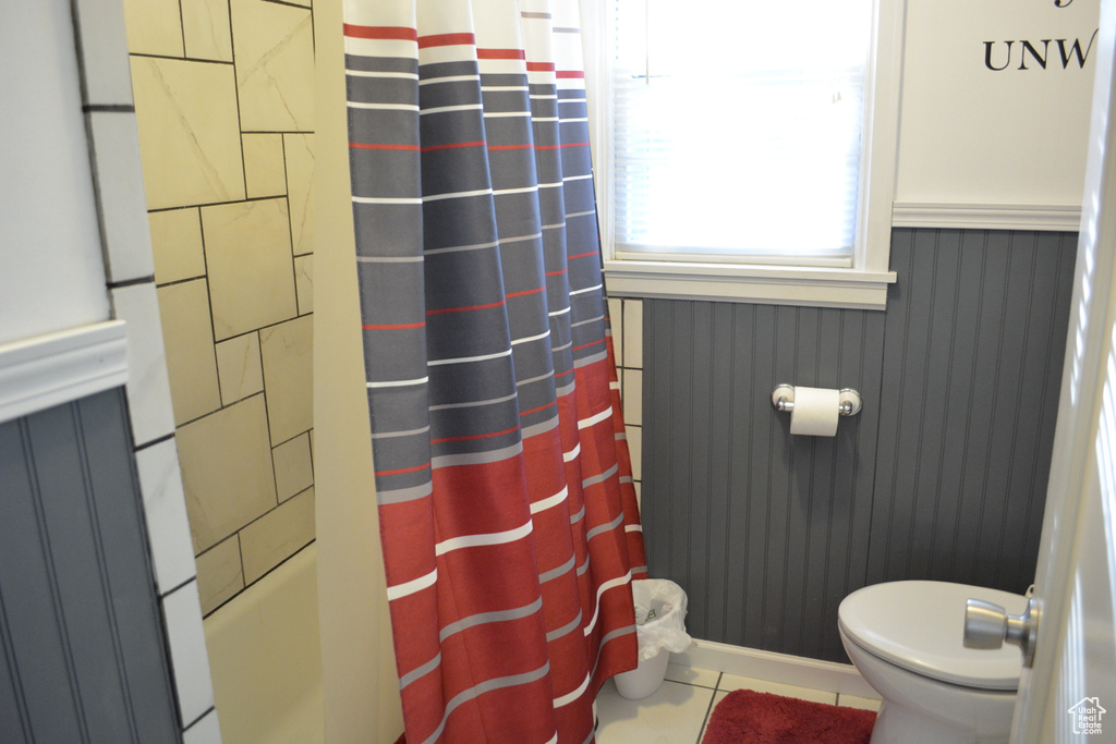 Bathroom with tile patterned flooring, shower / bath combo, and a wainscoted wall