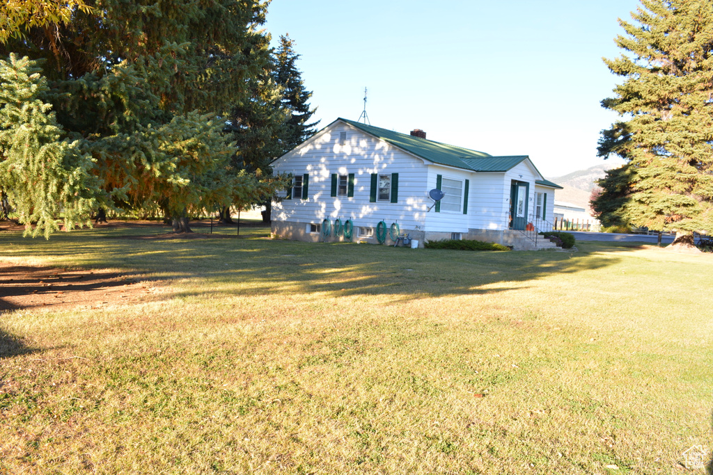 View of property exterior featuring a yard and a chimney