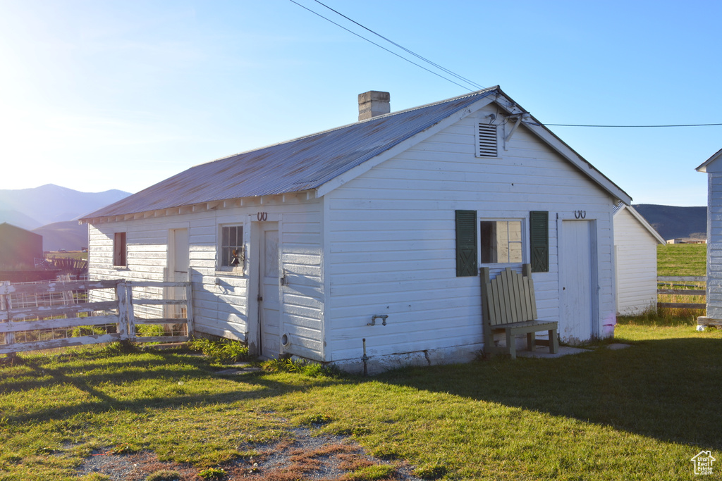 Back of house with a chimney and a metal roof