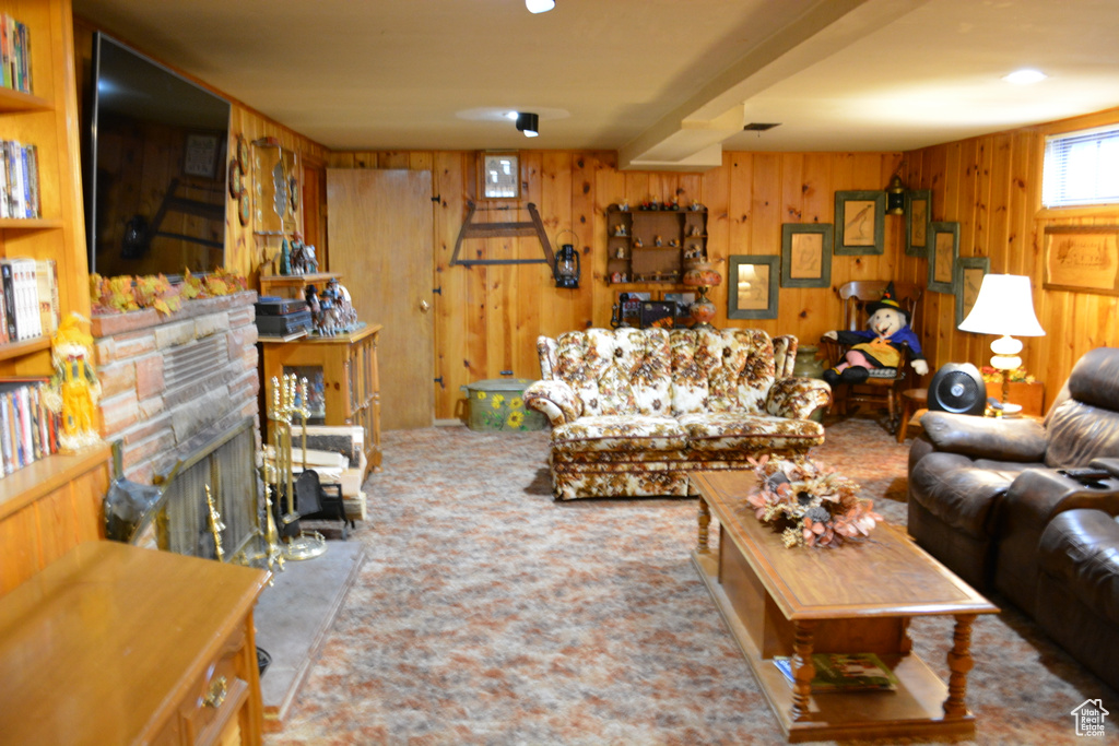 Living area featuring wooden walls, a fireplace, and carpet