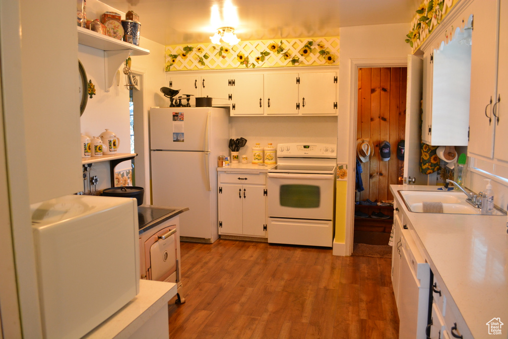 Kitchen with white appliances, white cabinetry, light countertops, and dark wood finished floors