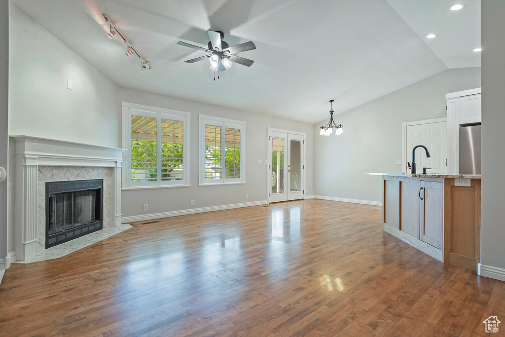Unfurnished living room with ceiling fan, vaulted ceiling, a premium fireplace, recessed lighting, and wood finished floors