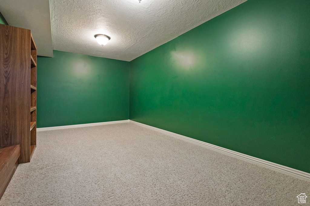 Carpeted spare room with a textured ceiling and baseboards