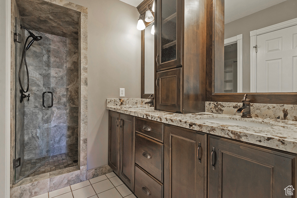 Bathroom featuring a stall shower, double vanity, and tile patterned flooring