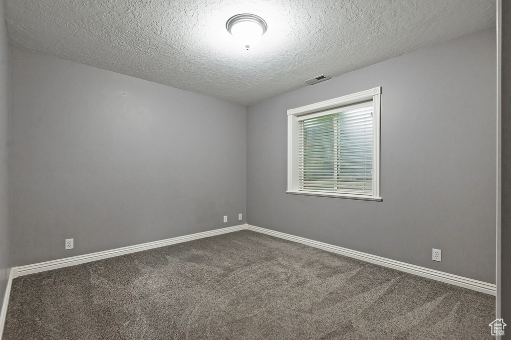 Empty room with a textured ceiling and carpet flooring