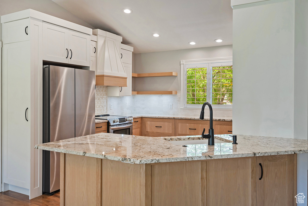 Kitchen featuring appliances with stainless steel finishes, recessed lighting, light stone countertops, backsplash, and custom range hood