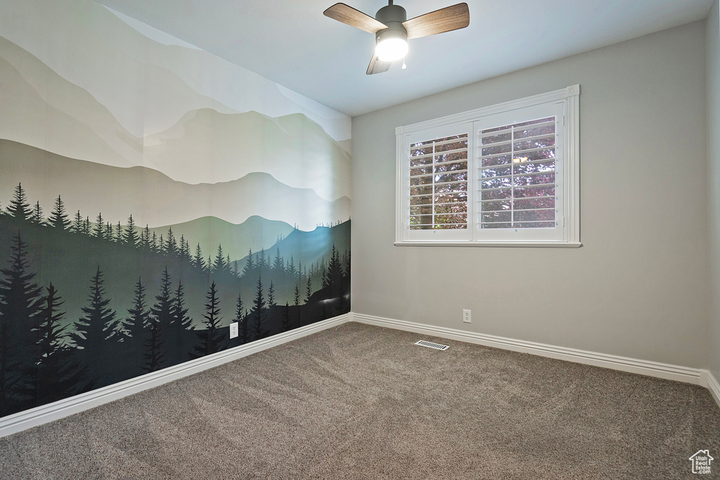 Carpeted spare room featuring baseboards and a ceiling fan