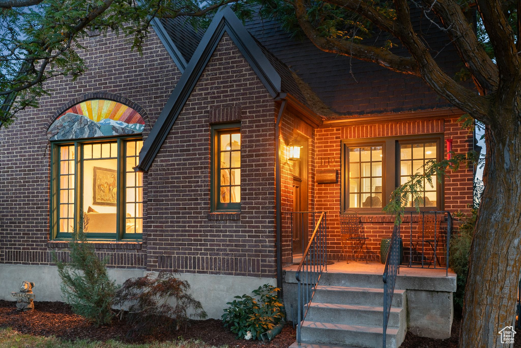 View of front of property featuring brick siding and a shingled roof