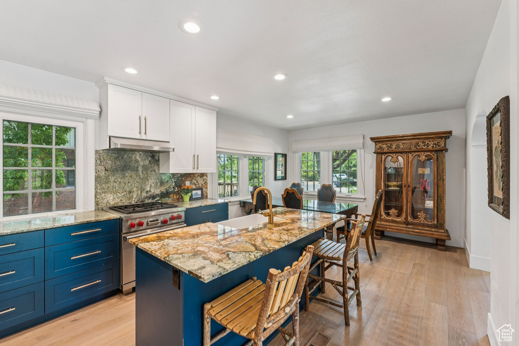 Kitchen with premium stove, white cabinets, light wood finished floors, recessed lighting, and light stone counters