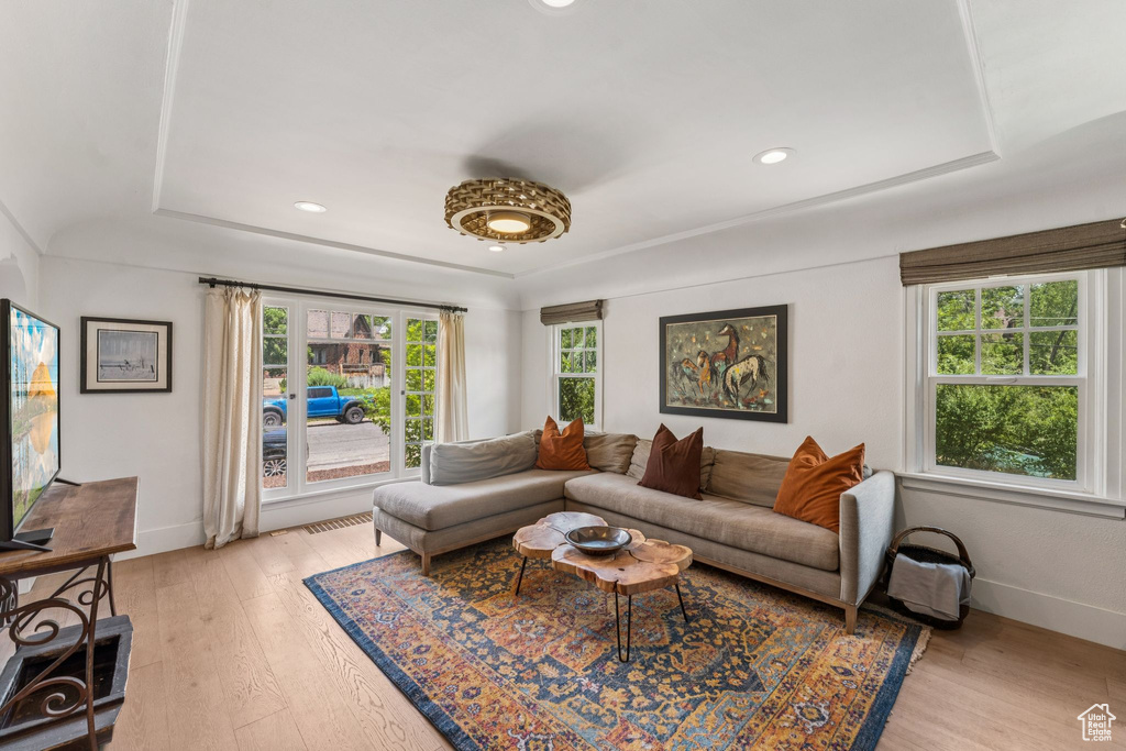 Living area with a raised ceiling, light wood-style flooring, and recessed lighting