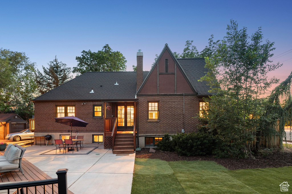 Back of property at dusk with brick siding, a patio area, a chimney, and outdoor dining space