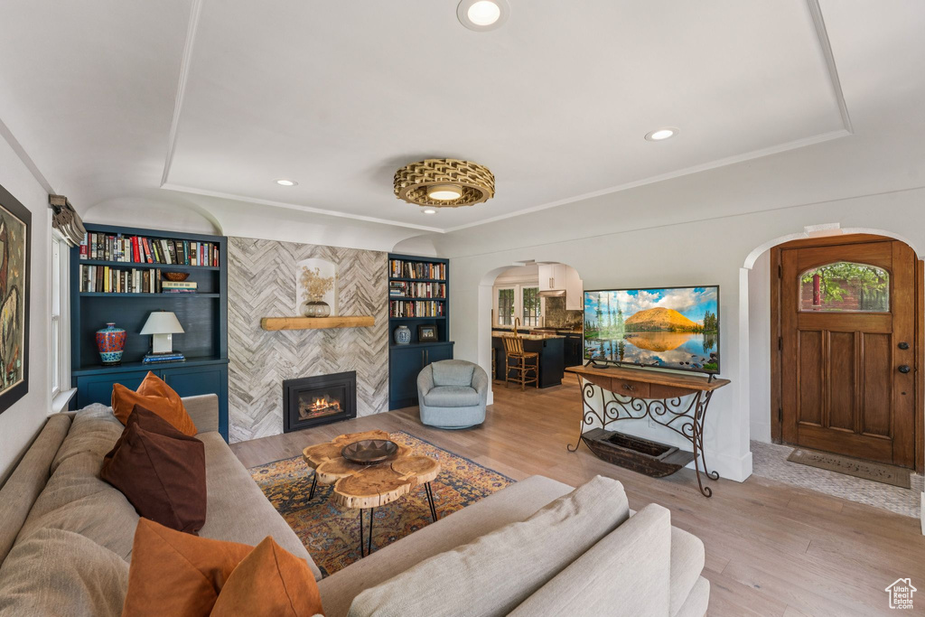 Living area with arched walkways, wood finished floors, a fireplace, recessed lighting, and crown molding