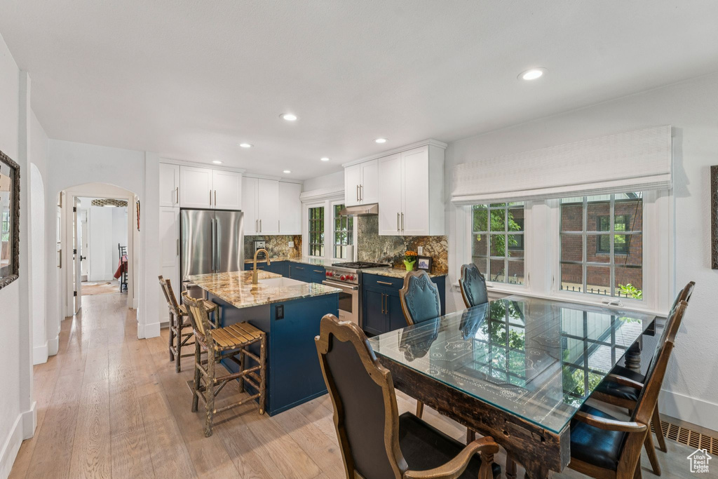 Dining room featuring arched walkways, light wood-style floors, healthy amount of natural light, and recessed lighting