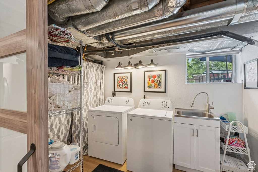 Washroom featuring washing machine and dryer, cabinet space, and light wood finished floors