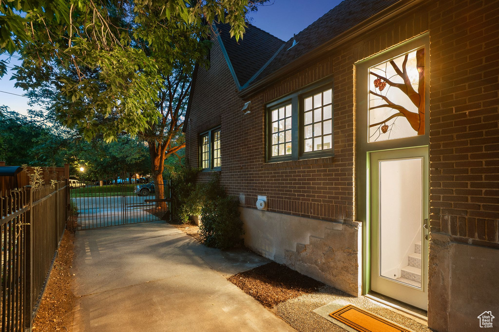 View of side of property featuring brick siding, a gate, and a shingled roof