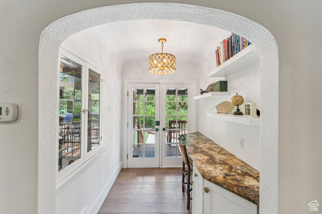 Doorway to outside with french doors, hardwood / wood-style flooring, a chandelier, and arched walkways
