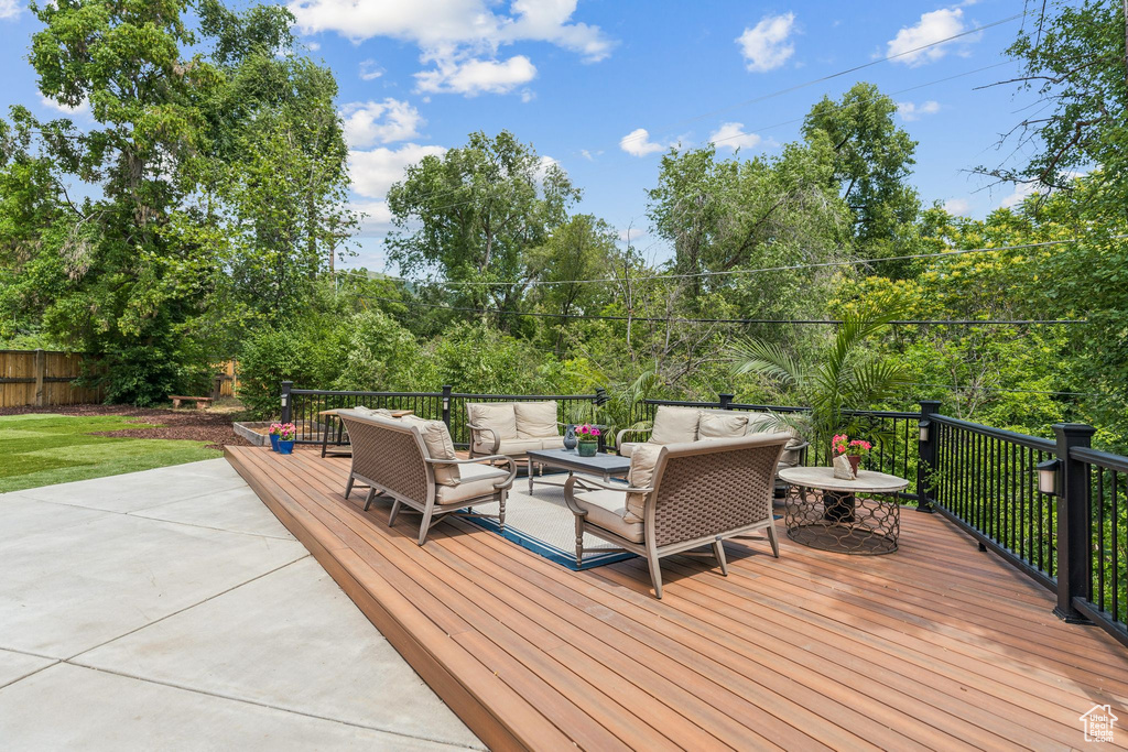 Wooden terrace with an outdoor hangout area and view of wooded area