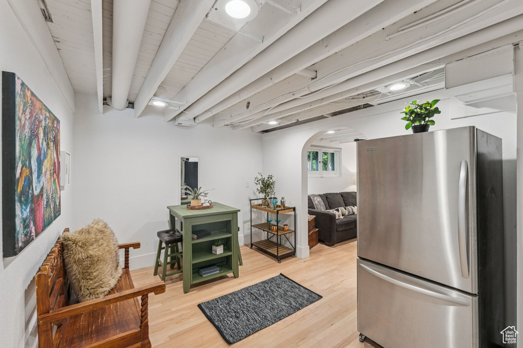 Kitchen featuring freestanding refrigerator, arched walkways, light wood finished floors, and open shelves