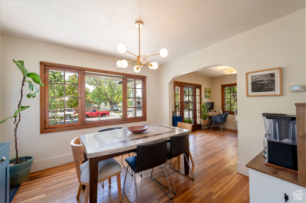 Dining area featuring arched walkways, light wood finished floors, and a chandelier