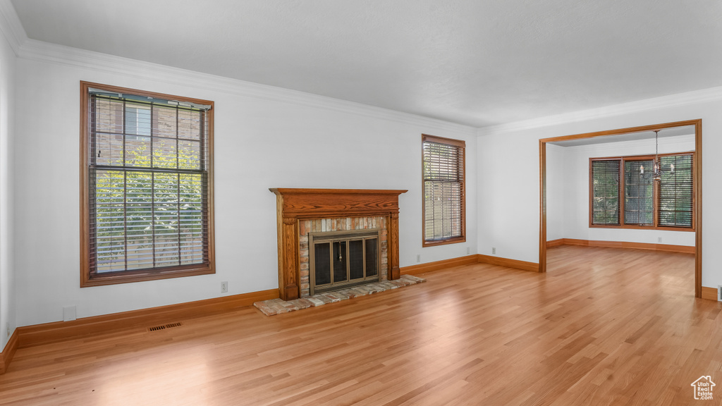 Unfurnished living room with wood finished floors, crown molding, and a fireplace