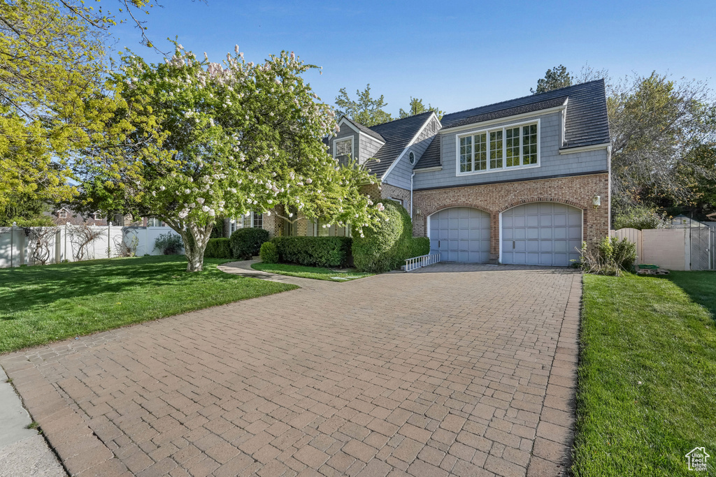 View of front facade featuring brick siding, decorative driveway, and a garage