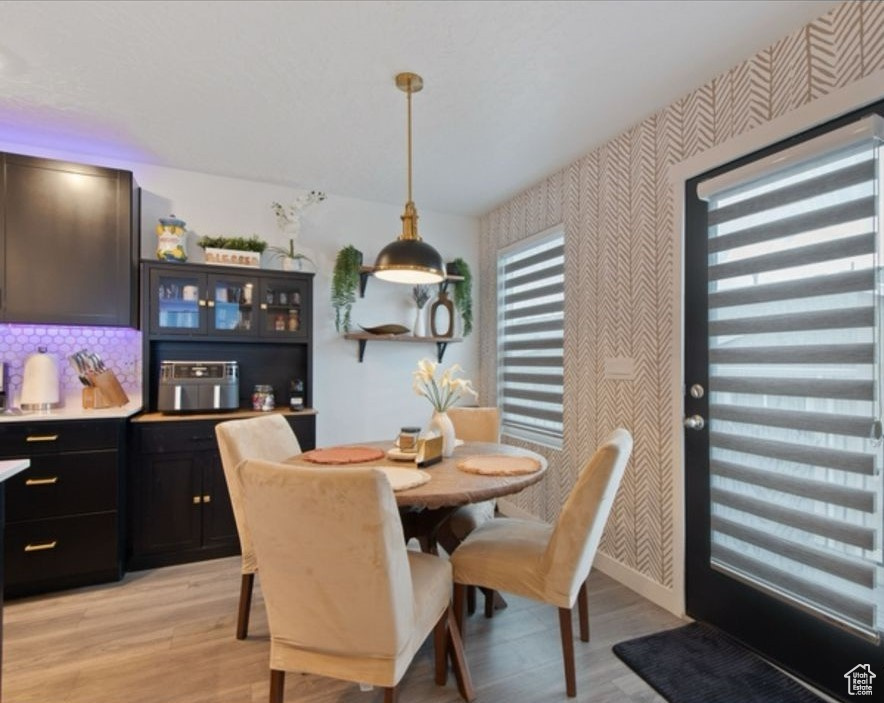 Dining area with wallpapered walls, light wood-style flooring, and baseboards