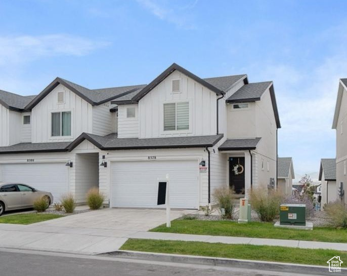 View of front of property featuring board and batten siding, a garage, and driveway