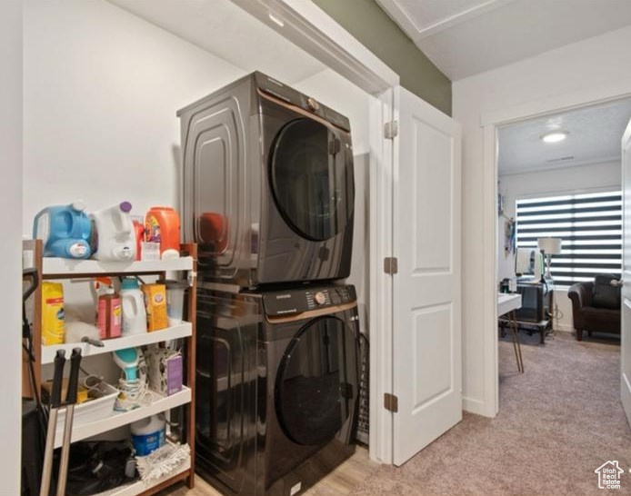 Washroom with estacked washer and dryer and carpet floors