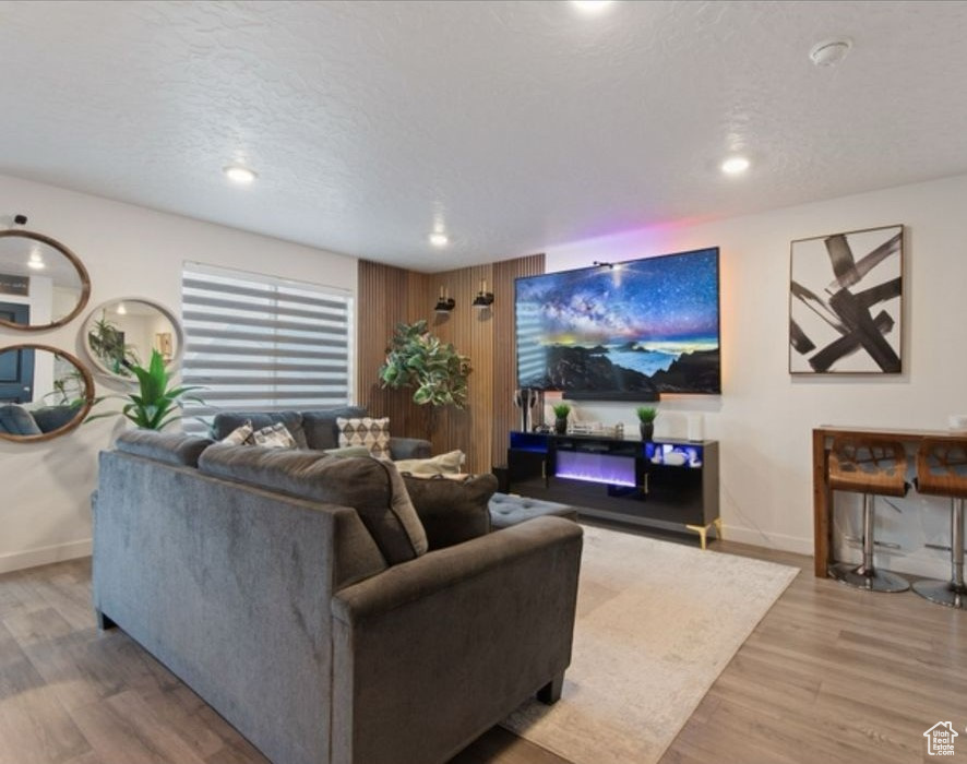 Living room featuring wood finished floors, baseboards, recessed lighting, and a textured ceiling