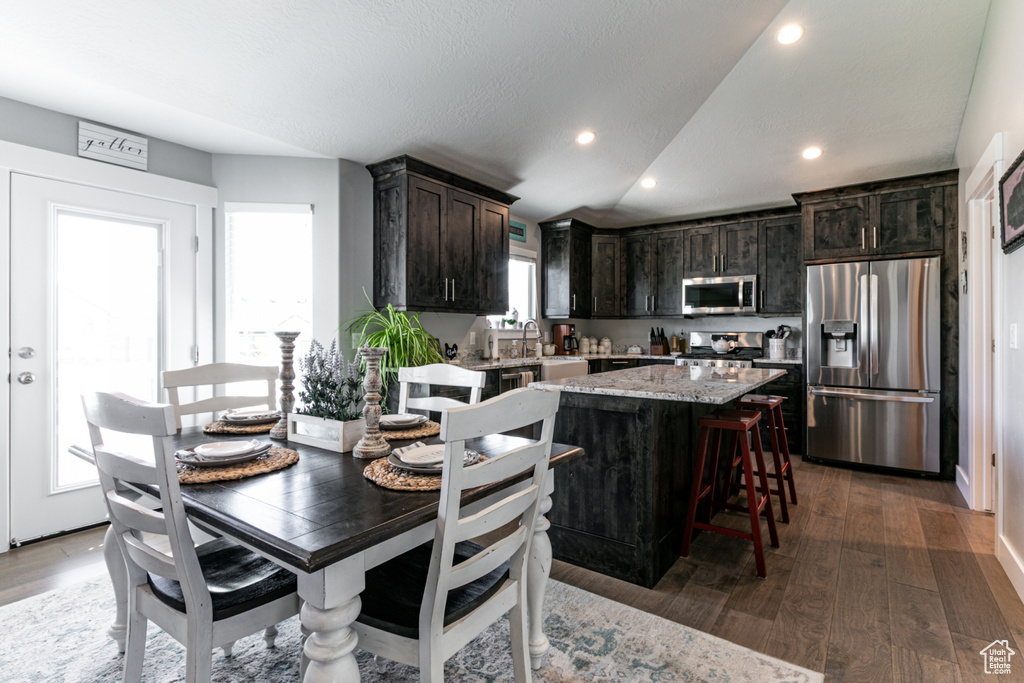 Dining space featuring dark wood-style floors, recessed lighting, and vaulted ceiling