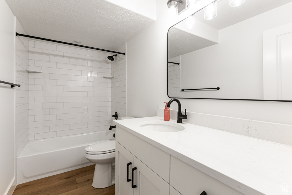 Full bathroom with vanity, wood finished floors, shower / tub combination, and a textured ceiling