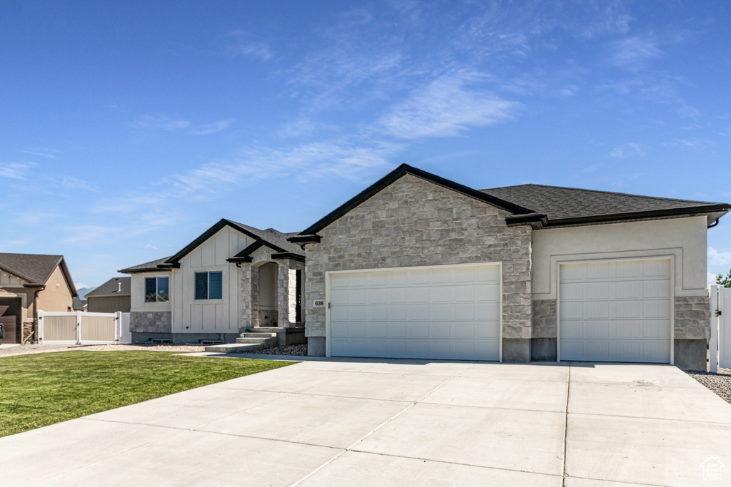 View of front of home featuring an attached garage, board and batten siding, driveway, and stone siding
