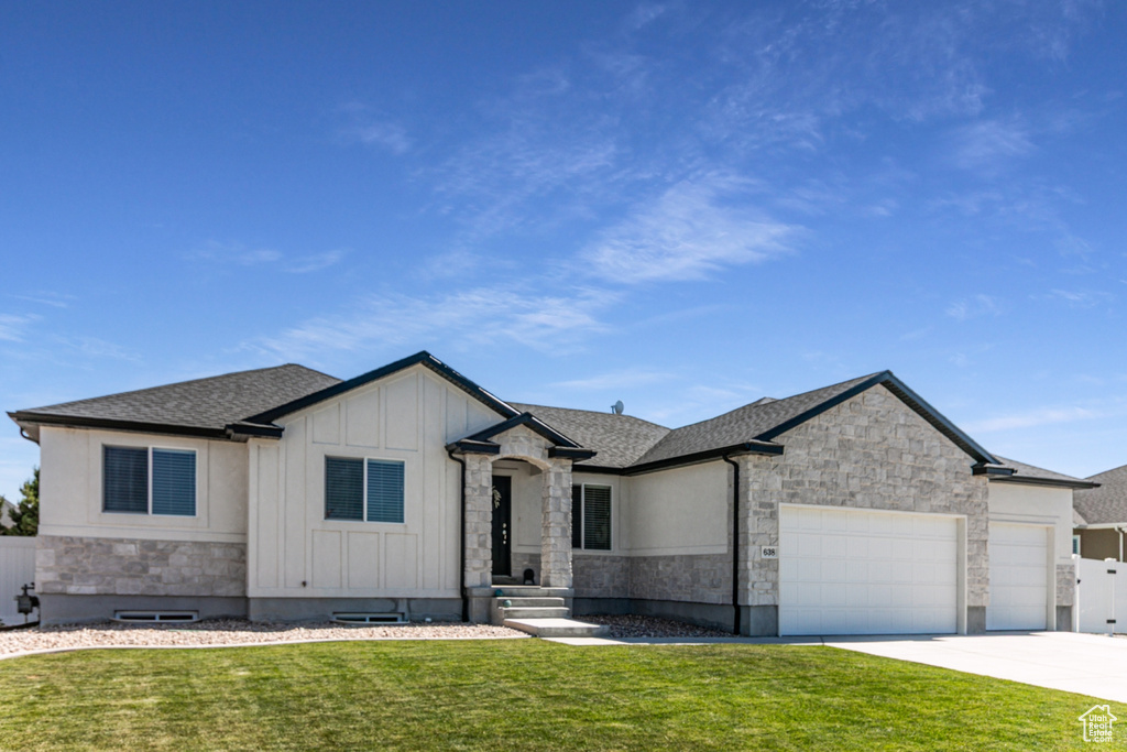 View of front of property with stone siding, an attached garage, board and batten siding, and roof with shingles
