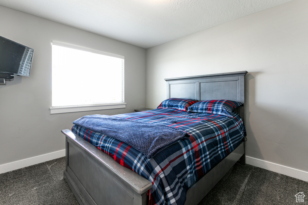 Bedroom featuring dark carpet and baseboards
