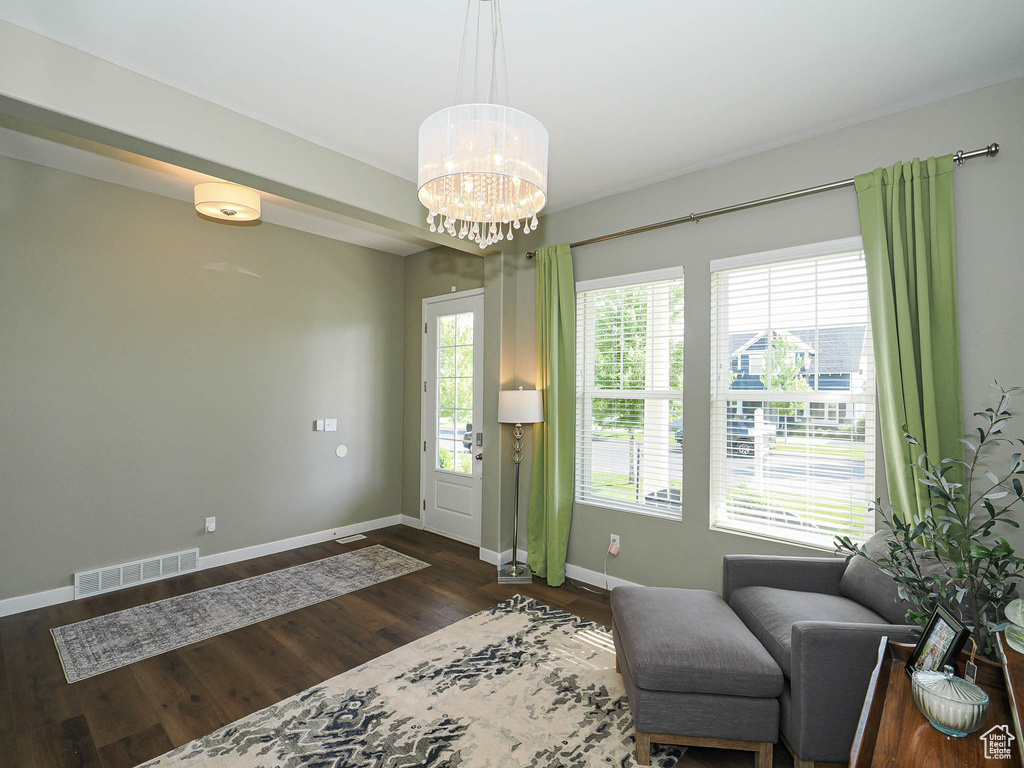 Sitting room with a chandelier and dark wood-type flooring