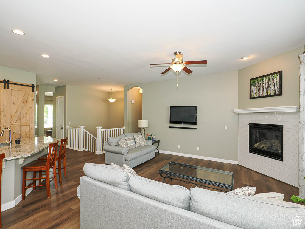 Living area with ceiling fan, recessed lighting, a barn door, dark wood-style flooring, and arched walkways