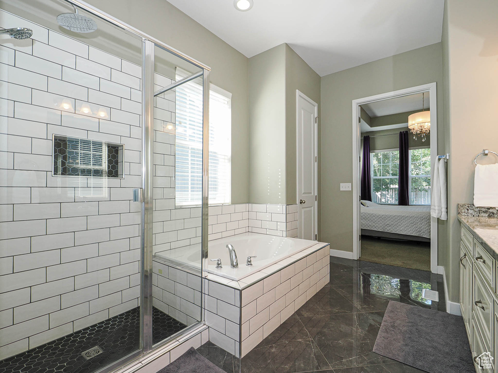 Full bathroom featuring a stall shower, a garden tub, marble tiled flooring, and vanity