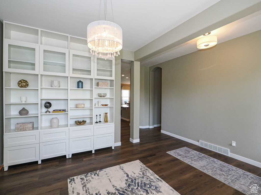 Unfurnished room with dark wood finished floors and a chandelier