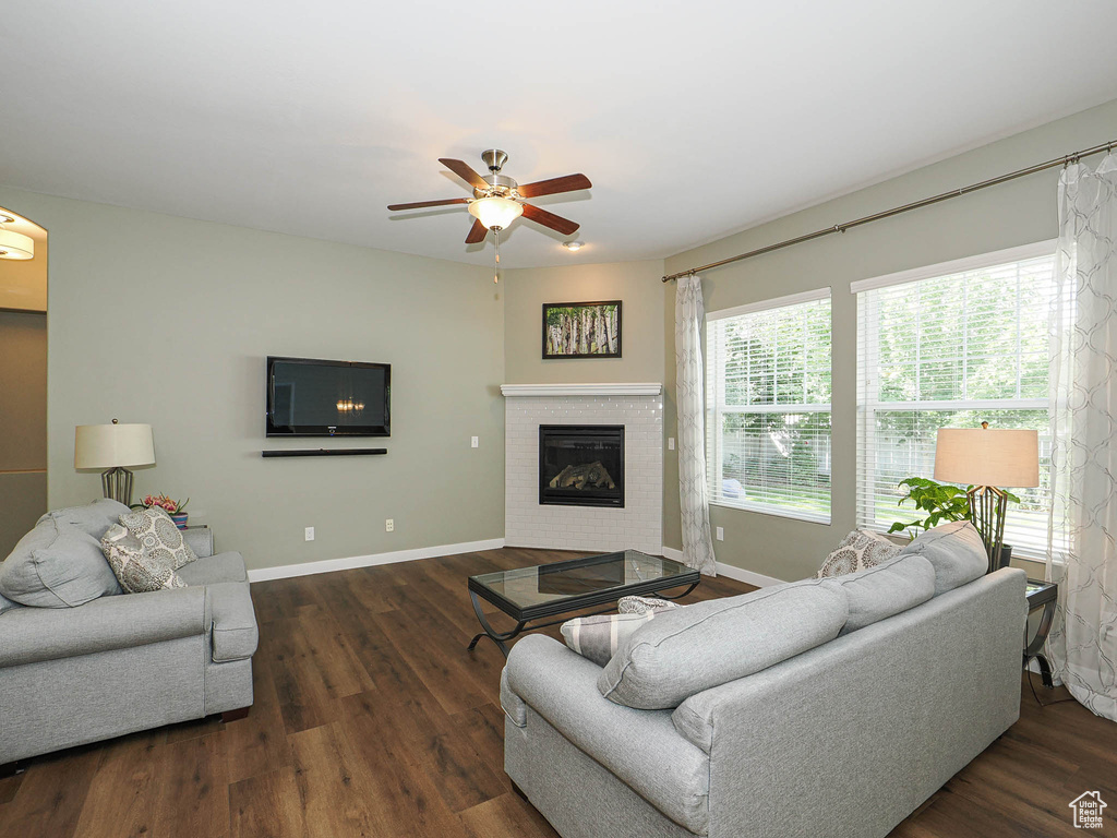Living area featuring ceiling fan, a glass covered fireplace, and wood finished floors