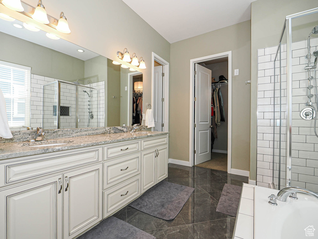 Bathroom featuring a stall shower, a walk in closet, double vanity, granite tiled floors, and a bath