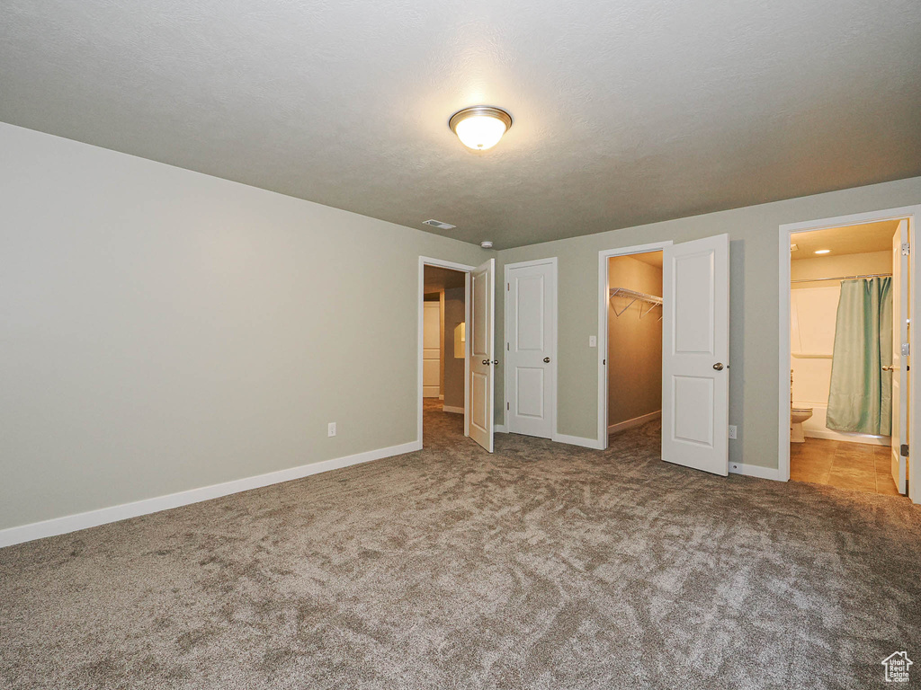 Unfurnished bedroom featuring carpet, a spacious closet, a closet, and connected bathroom