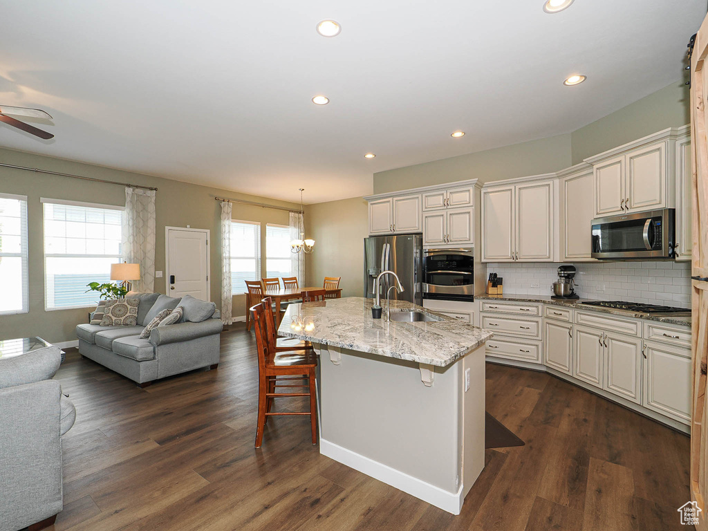 Kitchen with stainless steel appliances, open floor plan, a breakfast bar area, tasteful backsplash, and light stone counters