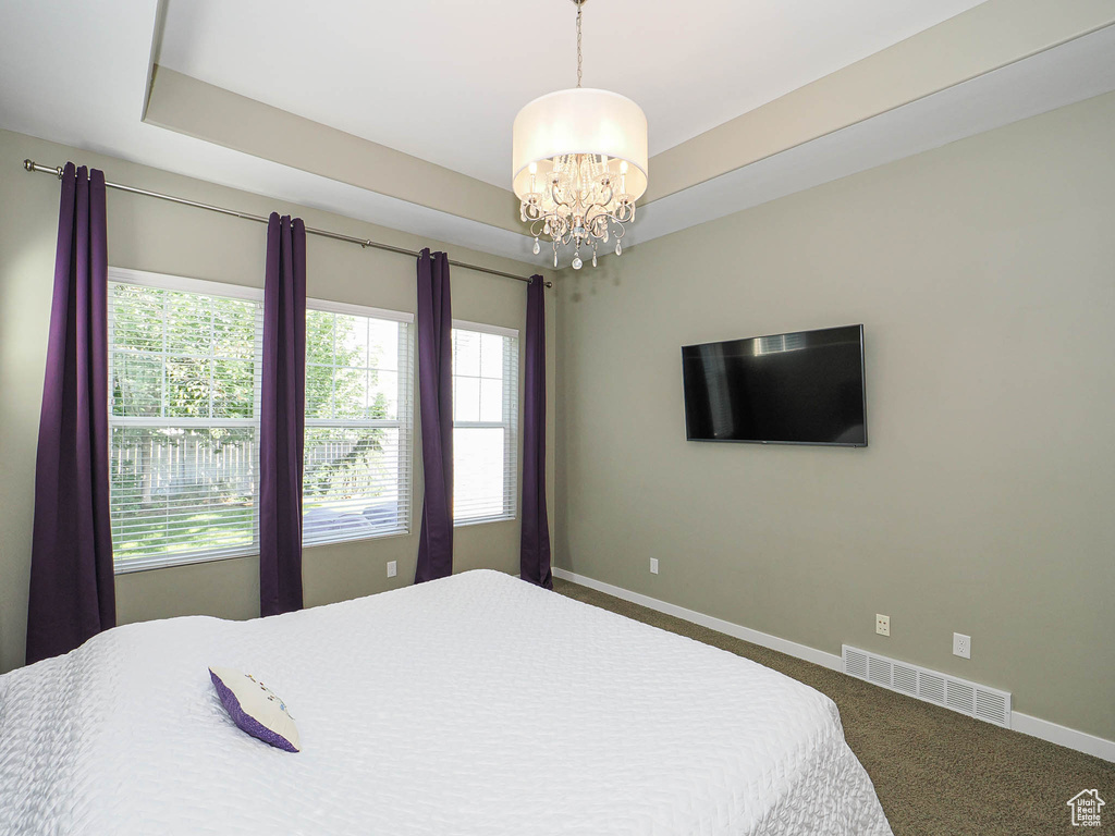 Carpeted bedroom with baseboards and a chandelier
